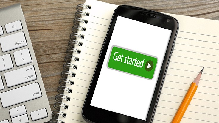 A cell phone reading "Get Started" next to a notepad and keyboard