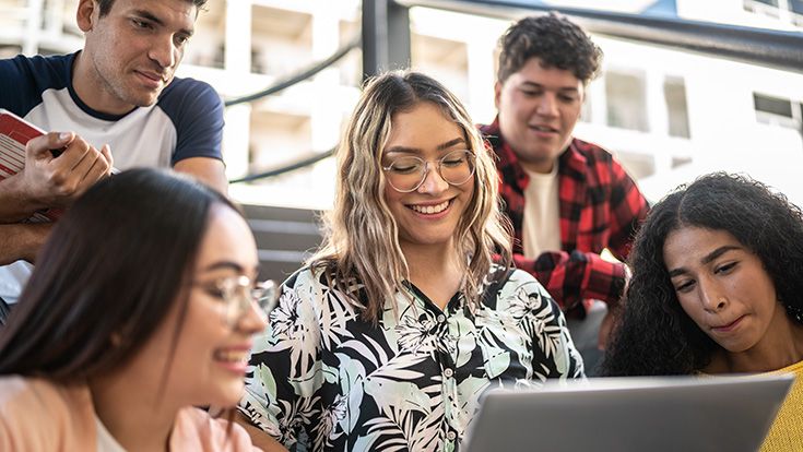 A group of Latinx students looking at a computer screen together